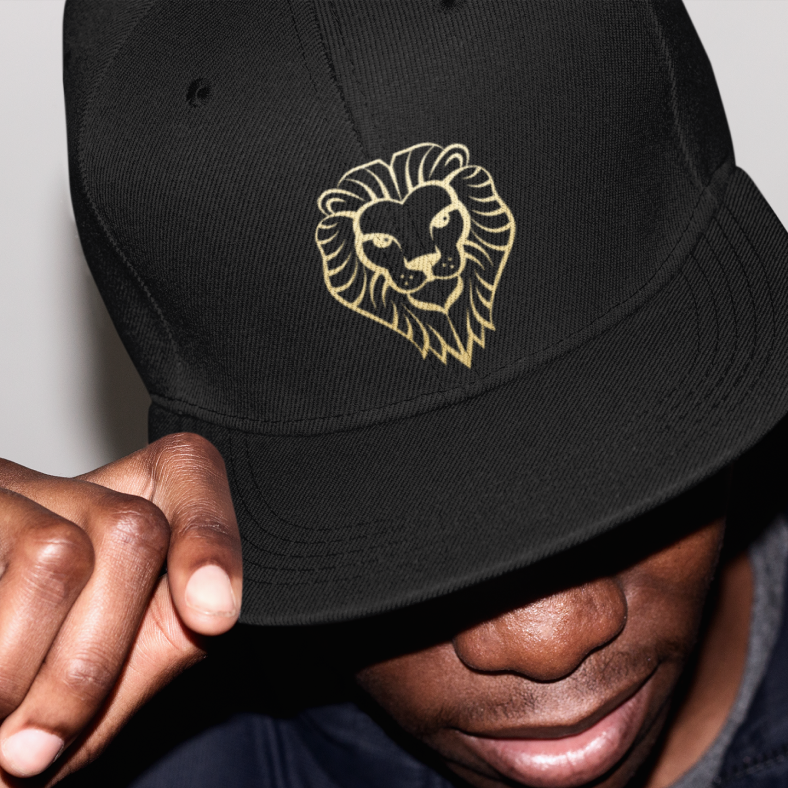 Lion face illustration shown in gold embroidery on a black baseball hat